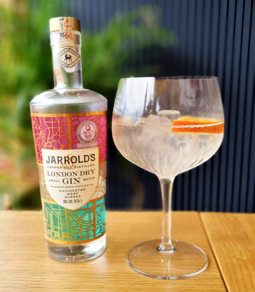 Joarrolds gin bottle with a glass of gin & tonic with a slice of orange