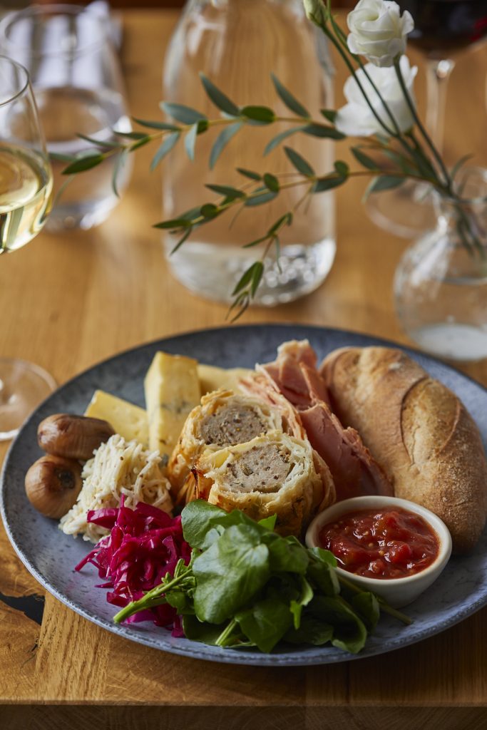 Dish with bread, sausage rolls, salad and relish on