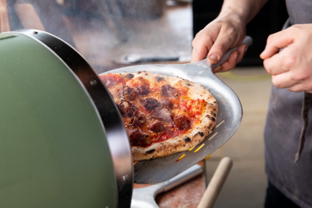 photo of pizza coming out of the oven